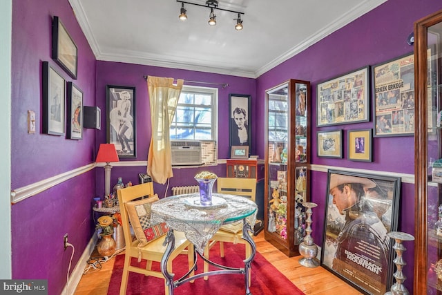 dining area featuring cooling unit, rail lighting, crown molding, and wood finished floors