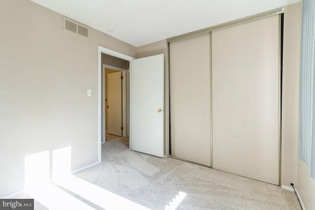 unfurnished bedroom with a closet and light carpet