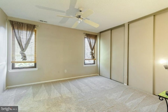 unfurnished bedroom featuring multiple closets, ceiling fan, and light colored carpet