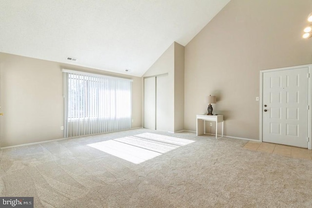 carpeted spare room with high vaulted ceiling