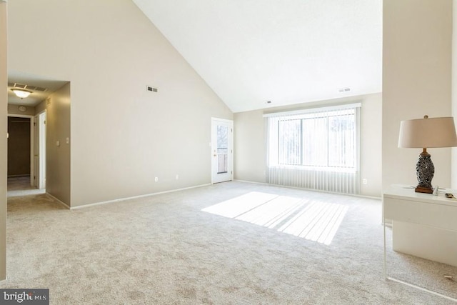 unfurnished living room with high vaulted ceiling and light carpet