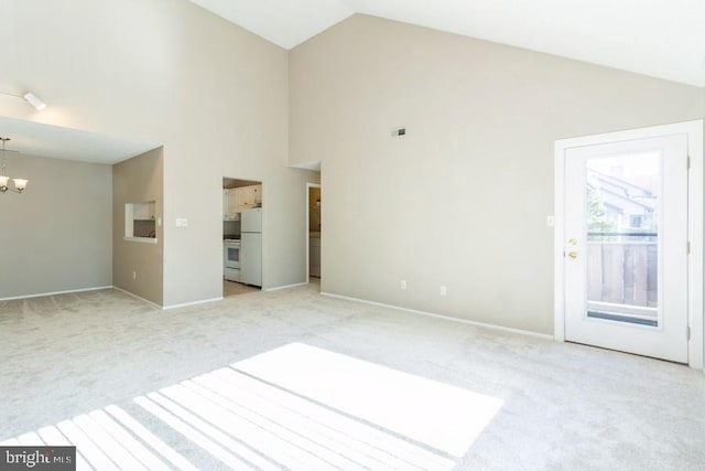 empty room with high vaulted ceiling, a chandelier, and light carpet