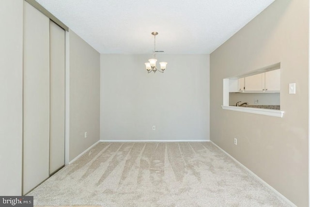 unfurnished room with an inviting chandelier and light carpet