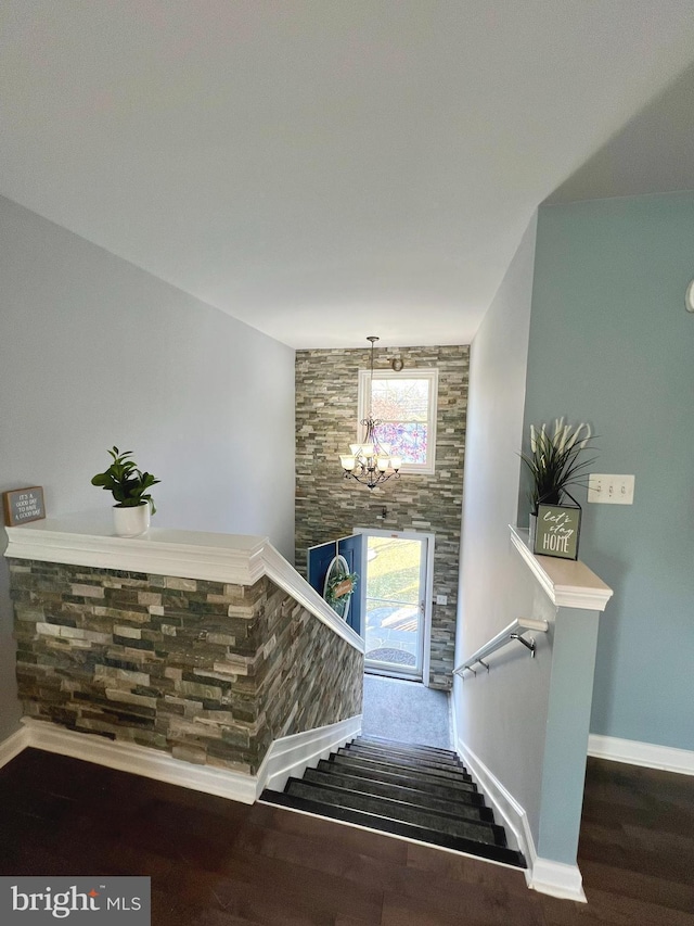 stairs featuring wood-type flooring and an inviting chandelier