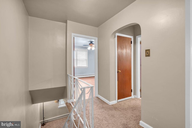 corridor featuring a baseboard heating unit and light colored carpet