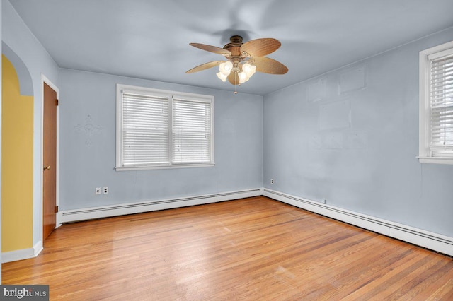 empty room with ceiling fan, baseboard heating, plenty of natural light, and light wood-type flooring