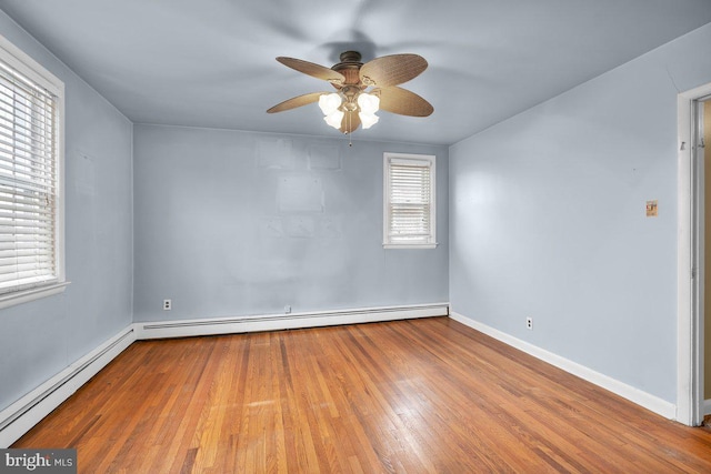 unfurnished room featuring baseboard heating, light hardwood / wood-style flooring, and a healthy amount of sunlight