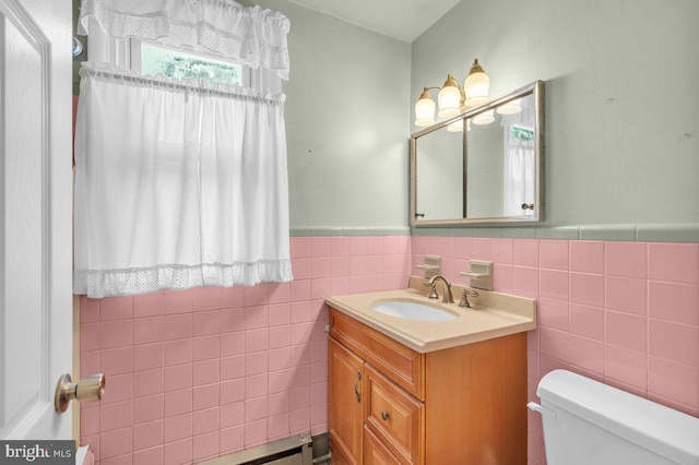 bathroom with toilet, vanity, and tile walls