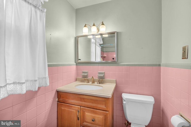 bathroom featuring toilet, tile walls, and vanity