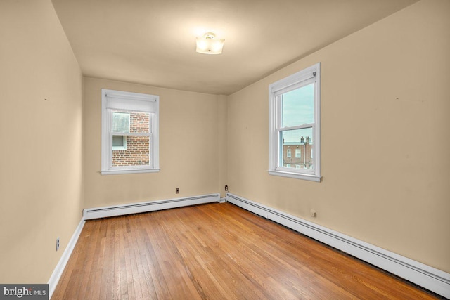 spare room featuring light hardwood / wood-style floors, a baseboard radiator, and plenty of natural light