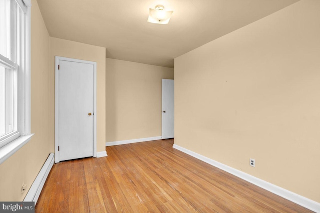 unfurnished room featuring baseboard heating and light hardwood / wood-style floors