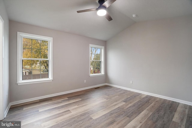 empty room featuring ceiling fan, vaulted ceiling, light hardwood / wood-style flooring, and plenty of natural light