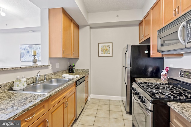 kitchen featuring light tile patterned floors, sink, light stone counters, and appliances with stainless steel finishes