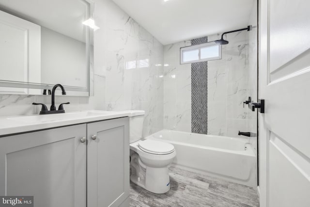 full bathroom featuring vanity, tiled shower / bath combo, hardwood / wood-style flooring, and toilet