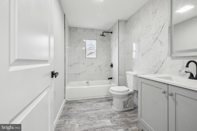 full bathroom with vanity, toilet, tiled shower / bath, and tile walls