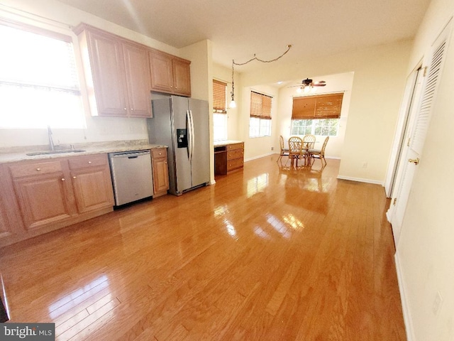 kitchen with stainless steel appliances, light wood-type flooring, ceiling fan, pendant lighting, and sink