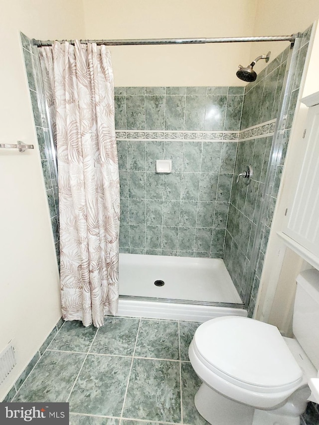 bathroom featuring a shower with shower curtain, tile patterned floors, and toilet