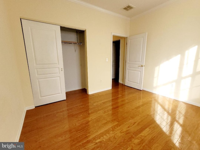 unfurnished bedroom featuring hardwood / wood-style floors, a closet, and crown molding