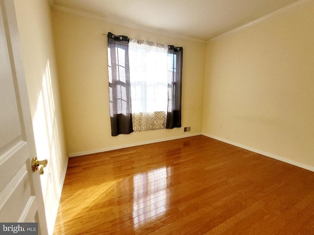 empty room featuring ornamental molding and hardwood / wood-style flooring