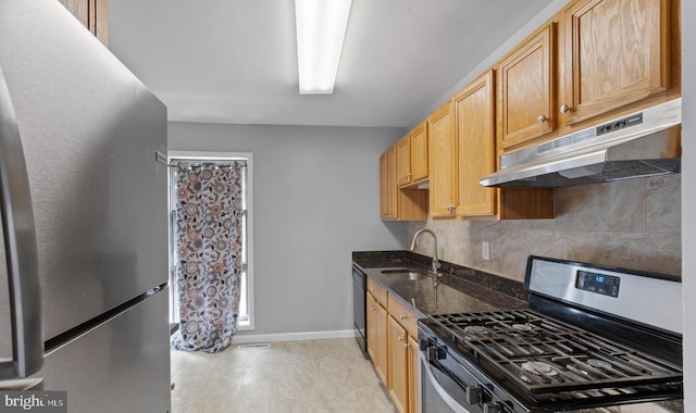 kitchen featuring sink, stainless steel appliances, dark stone counters, and tasteful backsplash