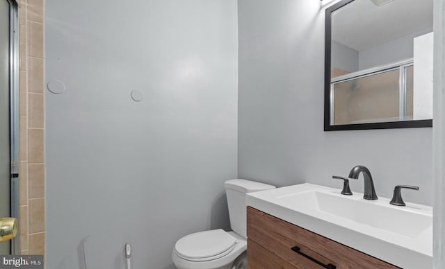 bathroom featuring toilet, a shower with door, and vanity