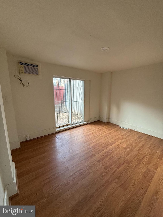 empty room featuring light wood-type flooring and a wall mounted AC