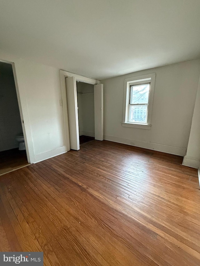 unfurnished bedroom featuring ensuite bathroom and light hardwood / wood-style flooring