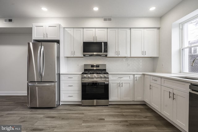 kitchen with sink, a healthy amount of sunlight, stainless steel appliances, white cabinets, and dark hardwood / wood-style flooring