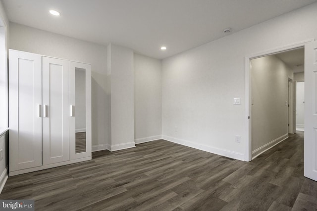 unfurnished bedroom with dark hardwood / wood-style floors and a closet