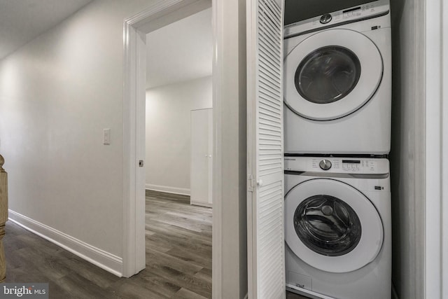 laundry area with stacked washer and dryer and dark hardwood / wood-style flooring