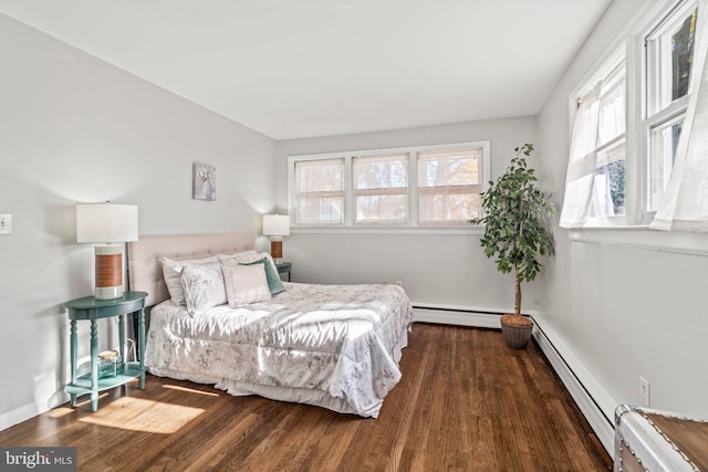 bedroom with dark hardwood / wood-style floors and a baseboard heating unit