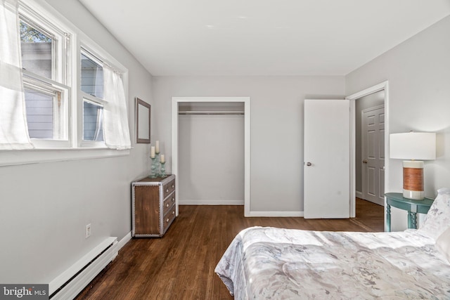 bedroom featuring dark wood-type flooring, a closet, and a baseboard heating unit