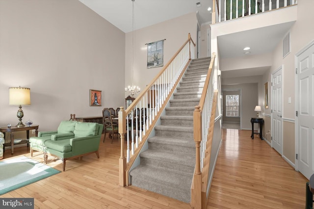 stairway featuring an inviting chandelier, hardwood / wood-style floors, and a high ceiling