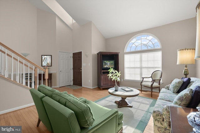 living room with high vaulted ceiling and light wood-type flooring