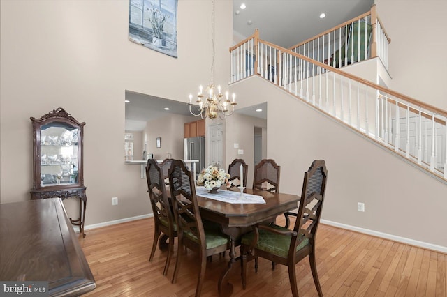 dining area with a high ceiling, a chandelier, and light hardwood / wood-style flooring