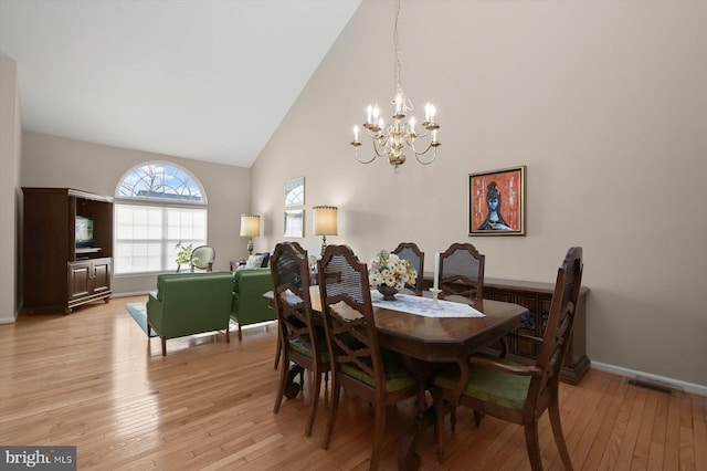 dining room featuring high vaulted ceiling, light hardwood / wood-style floors, and a chandelier