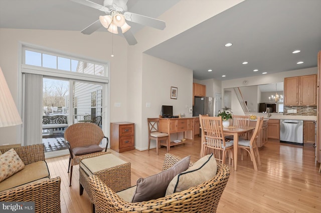 living room with ceiling fan with notable chandelier and light hardwood / wood-style flooring