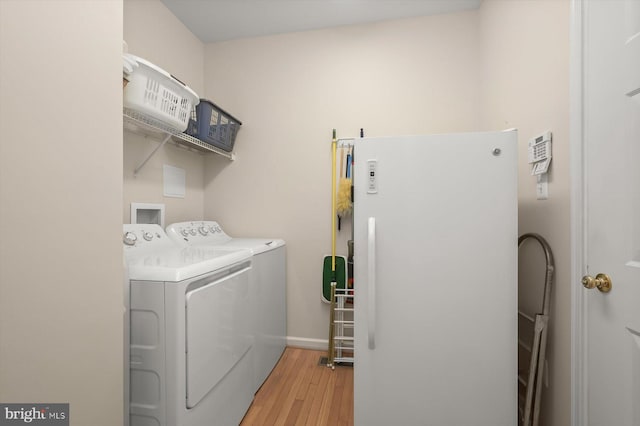 laundry room featuring separate washer and dryer and light hardwood / wood-style floors