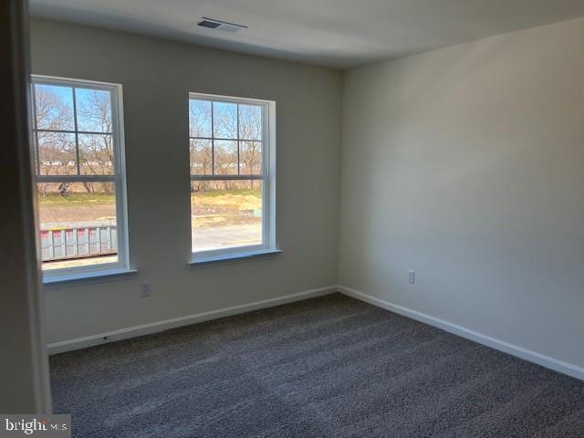spare room with visible vents, baseboards, and dark carpet