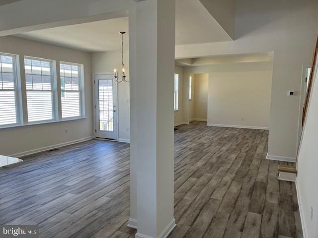interior space featuring wood finished floors, a notable chandelier, and baseboards