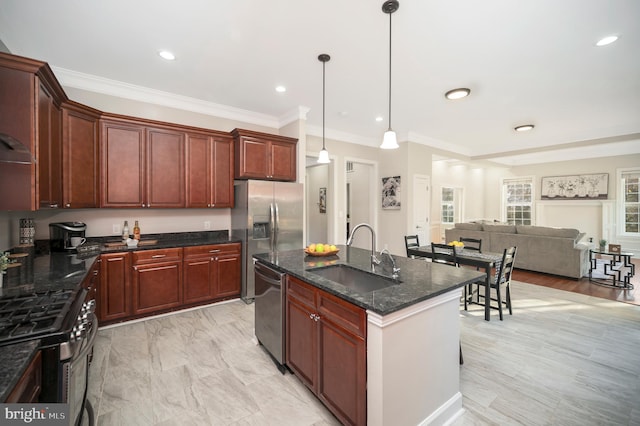 kitchen with pendant lighting, a kitchen island with sink, crown molding, sink, and appliances with stainless steel finishes