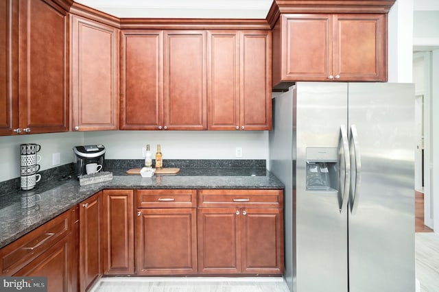 kitchen with stainless steel fridge with ice dispenser, light hardwood / wood-style flooring, and dark stone counters