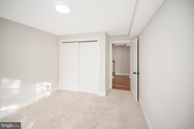 unfurnished bedroom with a closet and light colored carpet