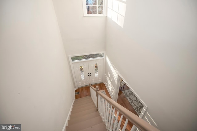 staircase with wood-type flooring and a towering ceiling