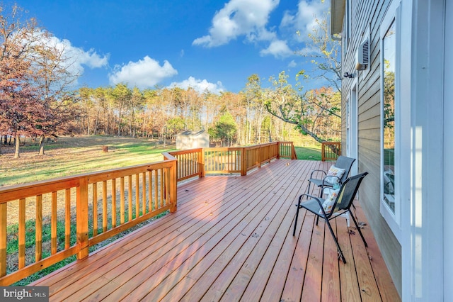 wooden terrace featuring a lawn and a shed