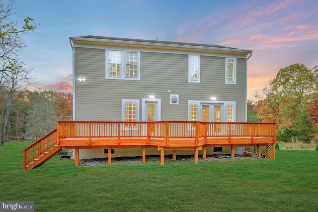 back house at dusk featuring a yard, a wooden deck, and french doors