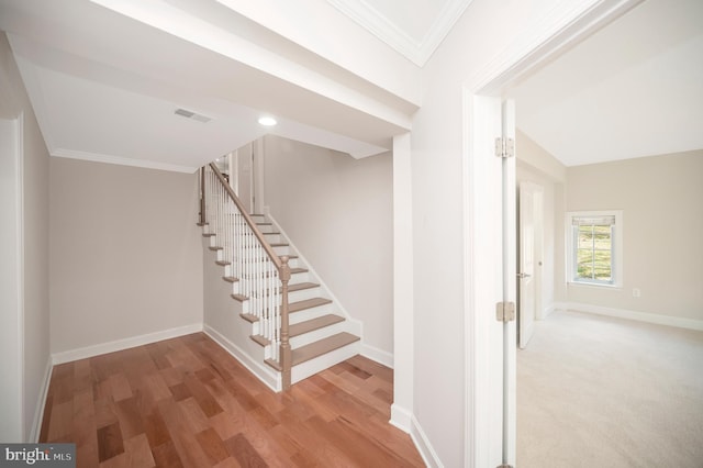 stairway with hardwood / wood-style floors and ornamental molding