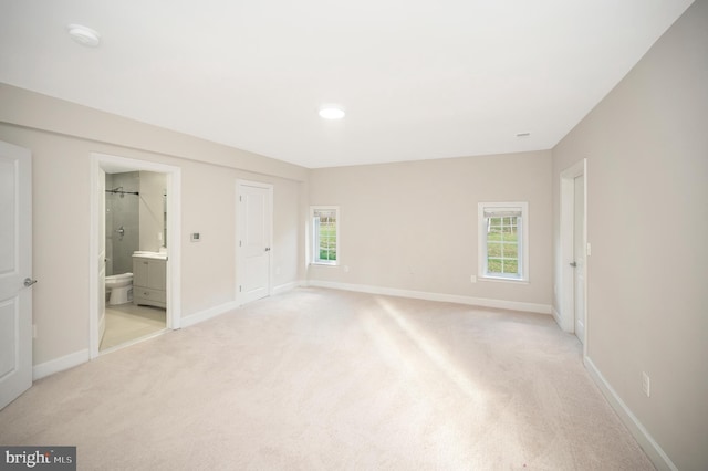 unfurnished bedroom featuring connected bathroom and light carpet