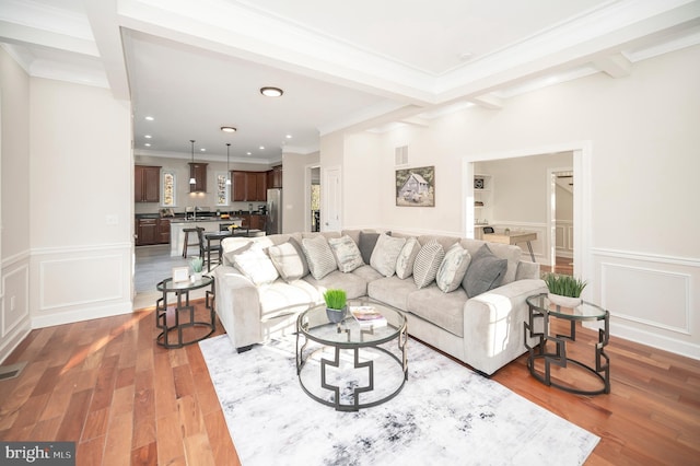 living room with sink, hardwood / wood-style floors, beamed ceiling, and ornamental molding