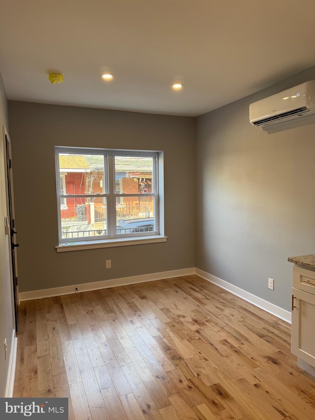 unfurnished dining area featuring light hardwood / wood-style floors and an AC wall unit